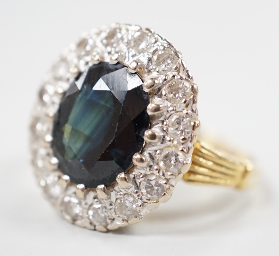 A 1970's? 18ct gold, single stone oval cut sapphire and illusion set diamond cluster ring, size O/P, gross weight 8.2 grams.